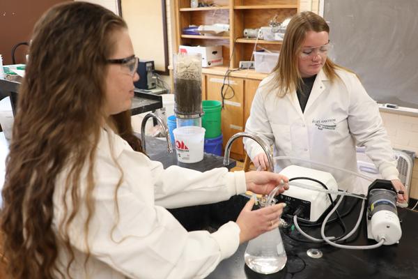 Two female 学生 using environmental equipment in a lab